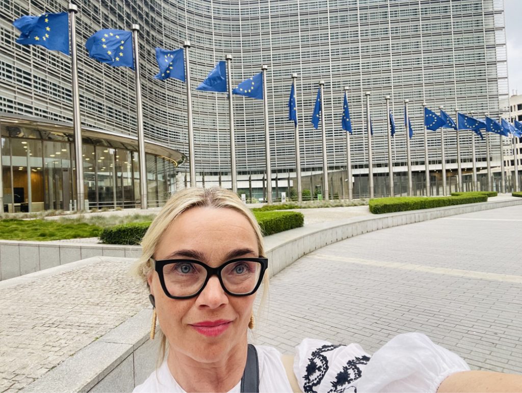 Terhi Tamminen ottaa selfien, taustalla rivi EU:n lippuja.